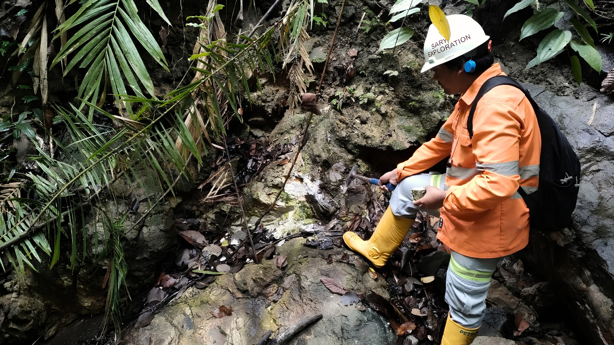 Geologists collecting soil and rock samples for geochemical exploration while analyzing elemental data to identify hidden mineral deposits during a mining exploration project in Indonesia